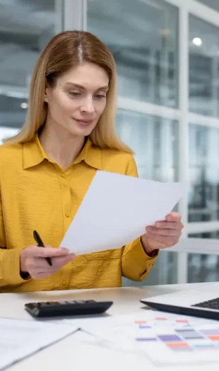 Young business woman, bookkeeper, financial analyst is focused in the office with documents and